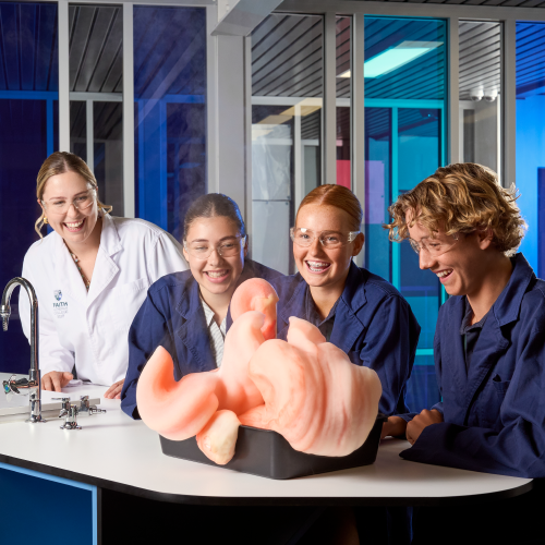 Four Faith Lutheran College Students crowd around their science experiment
