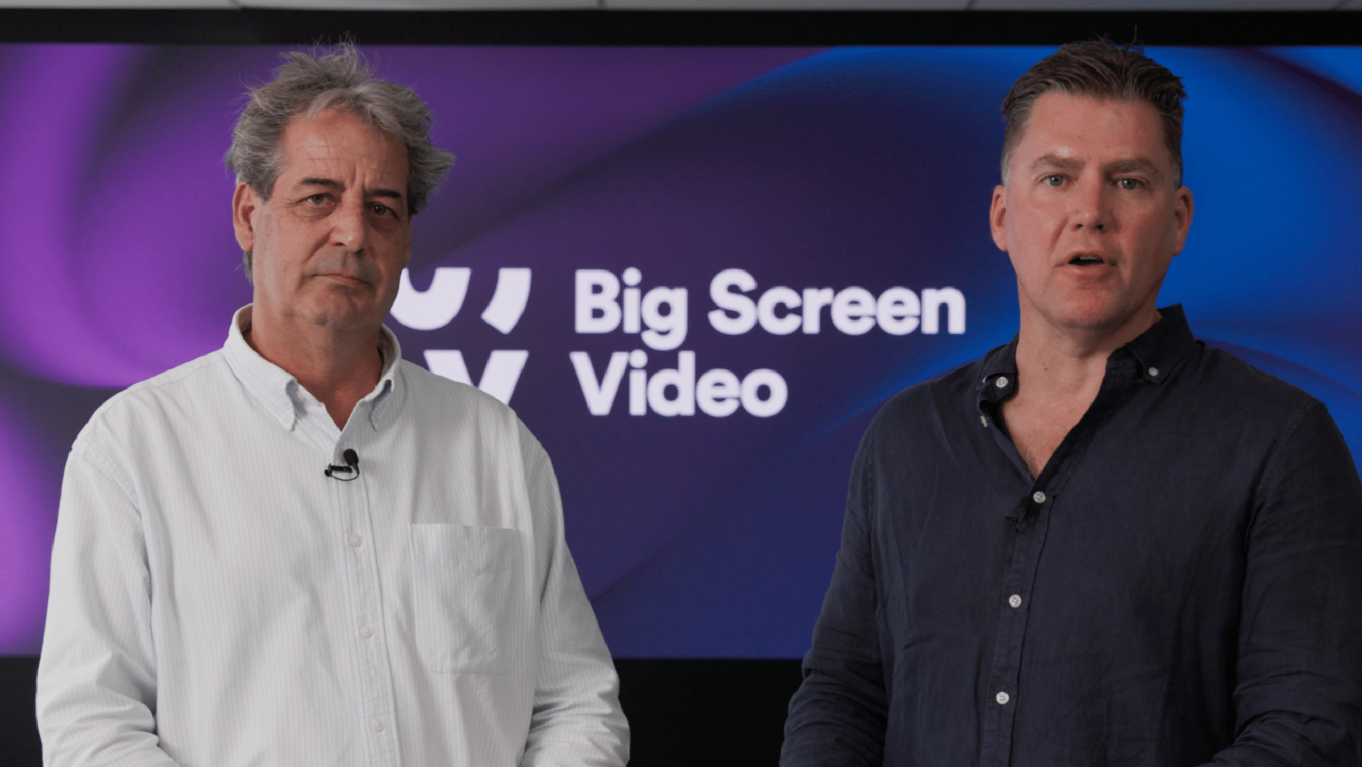 CEO Paul Ellery and COO Brett Delaney stand in front of the Big Screen Video logo and answer Q&A style questions
